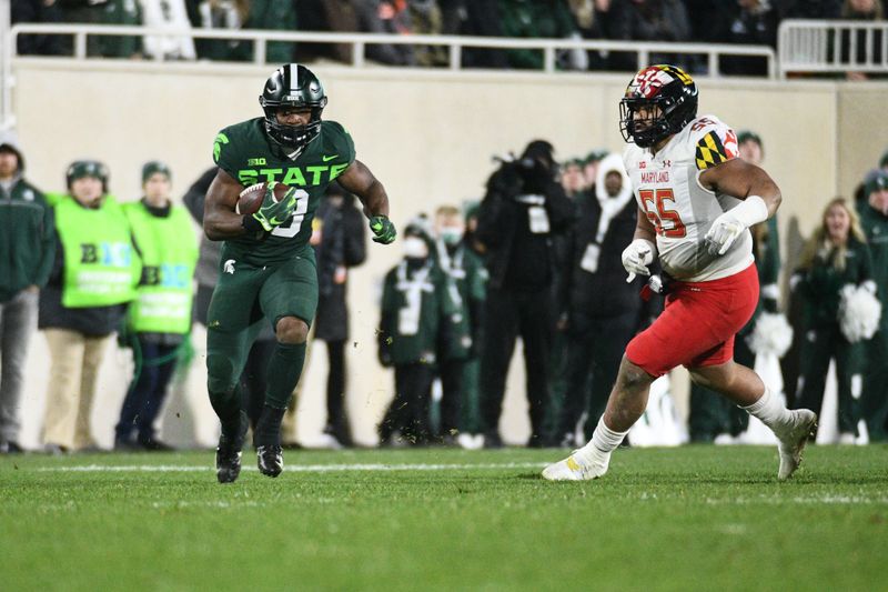 Nov 13, 2021; East Lansing, Michigan, USA;  Michigan State Spartans running back Kenneth Walker III (9) runs the ball against Maryland Terrapins defensive lineman Ami Finau (55) during the third quarter at Spartan Stadium. Mandatory Credit: Tim Fuller-USA TODAY Sports