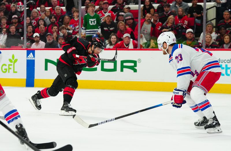 May 16, 2024; Raleigh, North Carolina, USA; Carolina Hurricanes center Jack Drury (18) gets the shot away against New York Rangers defenseman Adam Fox (23) during the first period in game six of the second round of the 2024 Stanley Cup Playoffs at PNC Arena. Mandatory Credit: James Guillory-USA TODAY Sports