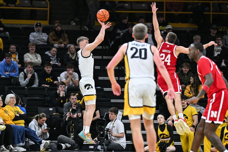 Jan 7, 2025; Iowa City, Iowa, USA; Iowa Hawkeyes guard Josh Dix (4) shoots the ball as Nebraska Cornhuskers guard Rollie Worster (24) defends and forward Payton Sandfort (20) looks on during the first half at Carver-Hawkeye Arena. Mandatory Credit: Jeffrey Becker-Imagn Images