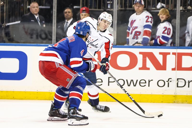 Apr 21, 2024; New York, New York, USA; Washington Capitals center Aliaksei Protas (21) attempts a shot on goal past New York Rangers defenseman Braden Schneider (4) in the third period in game one of the first round of the 2024 Stanley Cup Playoffs at Madison Square Garden. Mandatory Credit: Wendell Cruz-USA TODAY Sports