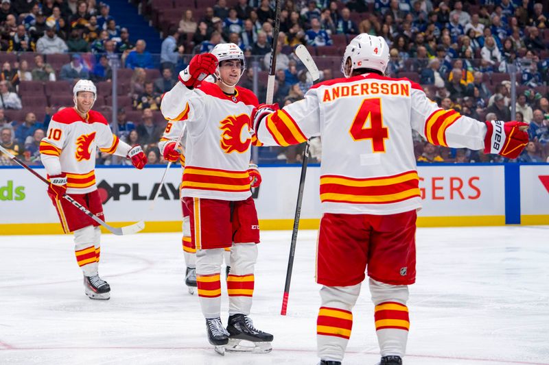 Oct 9, 2024; Vancouver, British Columbia, CAN; Calgary Flames forward Martin Pospisil (76) and defenseman Rasmus Andersson (4) celebrate Posposil’s goal against the Vancouver Canucks during the third period at Rogers Arena. Mandatory Credit: Bob Frid-Imagn Images