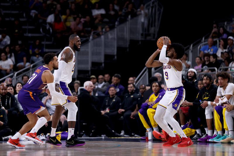 PALM SPRINGS, CALIFORNIA - OCTOBER 06: Bronny James #9 of the Los Angeles Lakers shoots against Tyus Jones #21 of the Phoenix Suns as teammate LeBron James #23 looks on during the second quarter at Acrisure Arena on October 06, 2024 in Palm Springs, California. NOTE TO USER: User expressly acknowledges and agrees that, by downloading and/or using this photograph, user is consenting to the terms and conditions of the Getty Images License Agreement. (Photo by Katelyn Mulcahy/Getty Images)