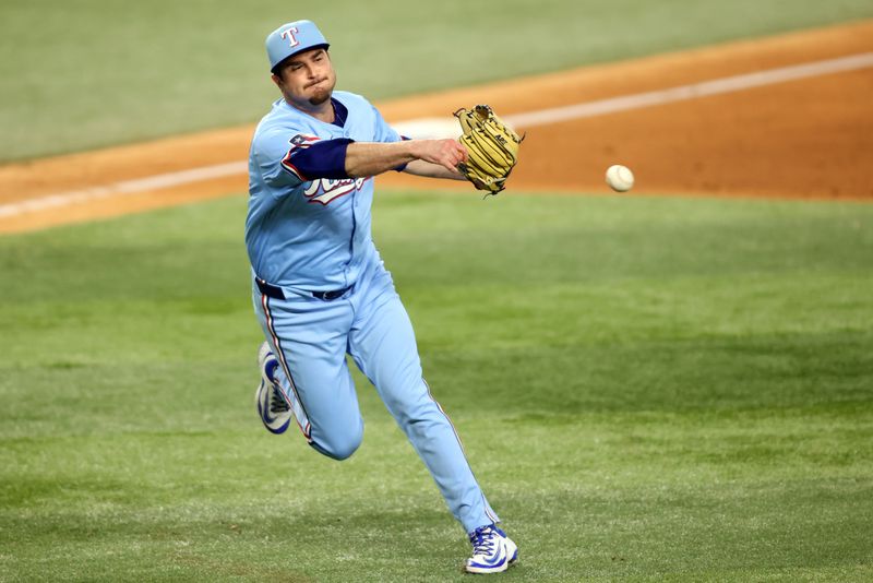 Jun 29, 2025; Arlington, Texas, USA; Texas Rangers pitcher Luke Jackson (77) fields a ground bal during the tenth inning against the Seattle Mariners at Globe Life Field. Mandatory Credit: Tim Heitman-Imagn Images