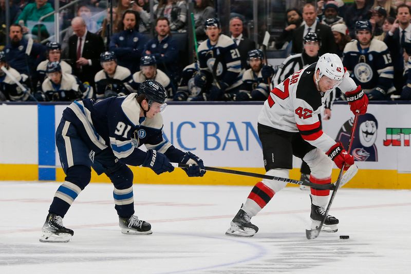 Mar 17, 2025; Columbus, Ohio, USA; New Jersey Devils right wing Curtis Lazar (42) carries the puck as Columbus Blue Jackets center Kent Johnson (91) trails the play during the second period at Nationwide Arena. Mandatory Credit: Russell LaBounty-Imagn Images