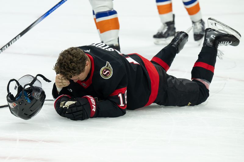 Nov 7, 2024; Ottawa, Ontario, CAN; Ottawa Senators center Tim Stutzle (18) falls to the ice after getting hit with the puck in the first period against the New York Islanders at the Canadian Tire Centre. Mandatory Credit: Marc DesRosiers-Imagn Images