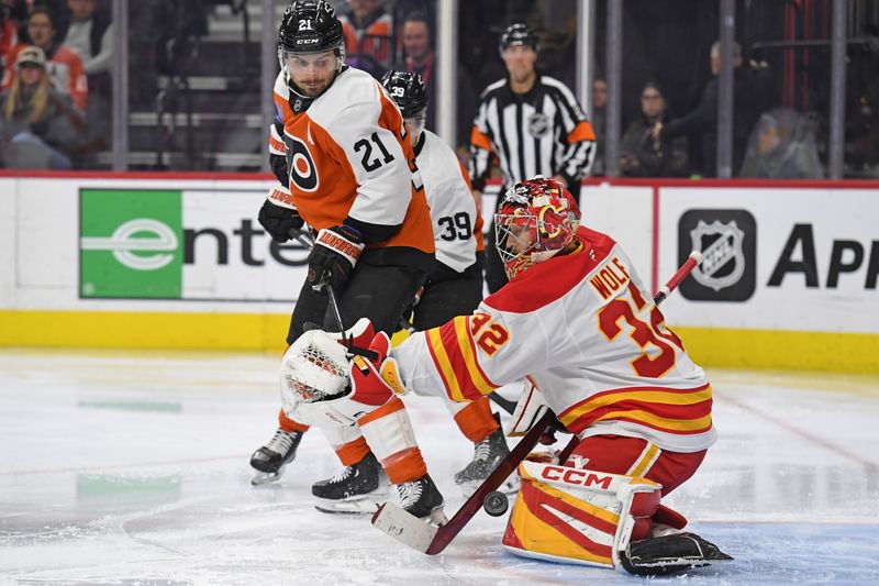 Mar 4, 2025; Philadelphia, Pennsylvania, USA; Calgary Flames goaltender Dustin Wolf (32) makes a save off a deflection by Philadelphia Flyers center Scott Laughton (21) during the third period at Wells Fargo Center. Mandatory Credit: Eric Hartline-Imagn Images