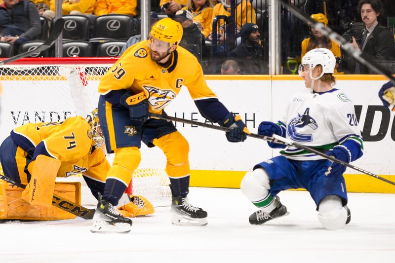 Jan 29, 2025; Nashville, Tennessee, USA;  Nashville Predators goaltender Juuse Saros (74) blocks the shot of Vancouver Canucks left wing Danton Heinen (20) during the second period at Bridgestone Arena. Mandatory Credit: Steve Roberts-Imagn Images