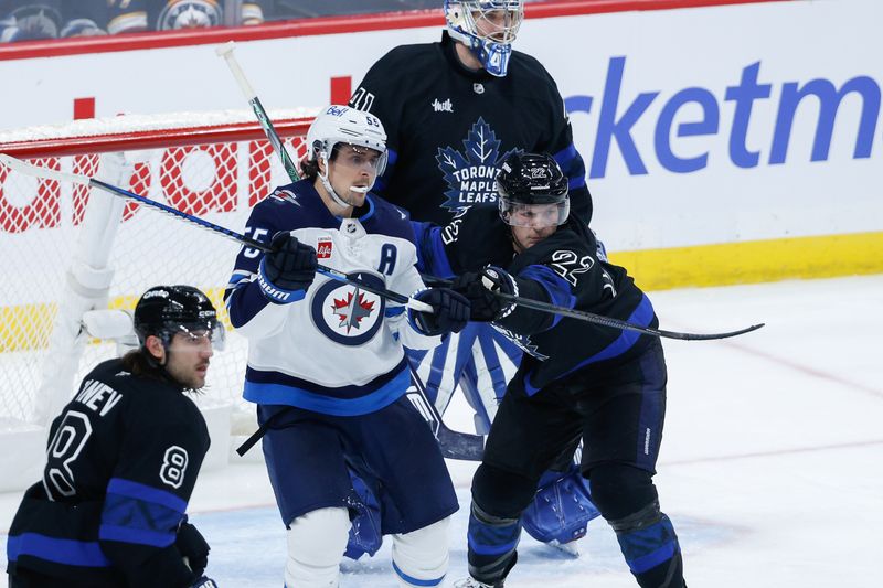 Oct 28, 2024; Winnipeg, Manitoba, CAN; Toronto Maple Leafs defenseman Jake McCabe (22) jostles for position with Winnipeg Jets forward Mark Scheifele (55) during the third period at Canada Life Centre. Mandatory Credit: Terrence Lee-Imagn Images