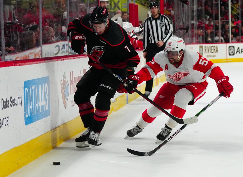 Jan 19, 2024; Raleigh, North Carolina, USA;  Carolina Hurricanes defenseman Dmitry Orlov (7) skates with the puck against Detroit Red Wings left wing David Perron (57) during the first period at PNC Arena. Mandatory Credit: James Guillory-USA TODAY Sports