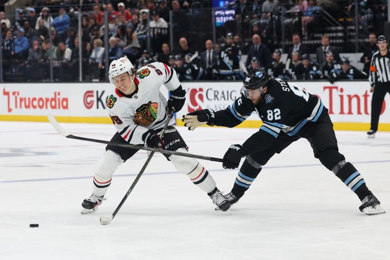 Feb 25, 2025; Salt Lake City, Utah, USA; Chicago Blackhawks center Connor Bedard (98) and Utah Hockey Club center Kevin Stenlund (82) battle for the puck during the second period at Delta Center. Mandatory Credit: Rob Gray-Imagn Images