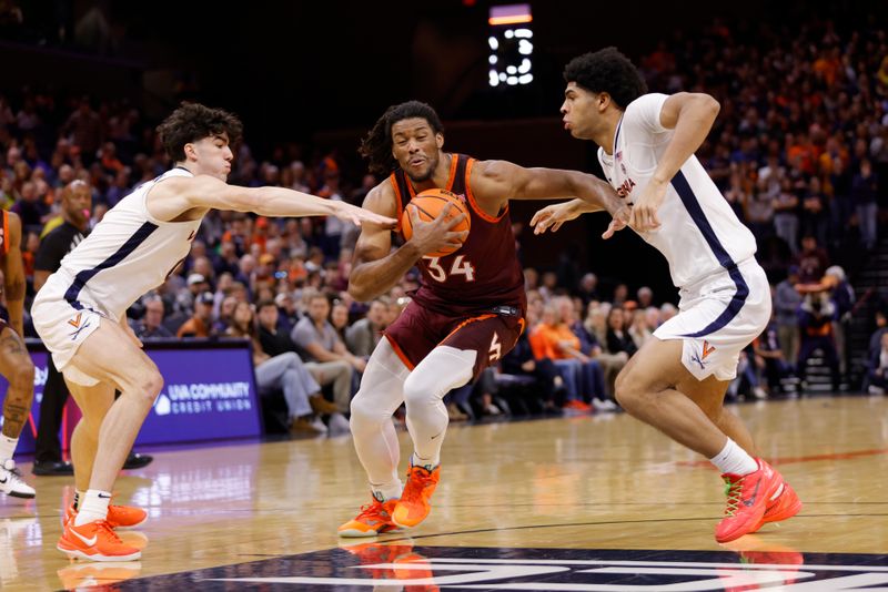 Feb 1, 2025; Charlottesville, Virginia, USA; Images Virginia Tech Hokies forward Mylyjael Poteat (34) controls the ball as Virginia Cavaliers forward Blake Buchanan (0) and Virginia Cavaliers forward Jacob Cofie (5) defends during the first half at John Paul Jones Arena. Mandatory Credit: Amber Searls-Imagn