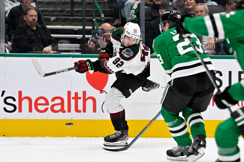 Nov 14, 2023; Dallas, Texas, USA; Arizona Coyotes center Logan Cooley (92) \shoots the puck in the Dallas Stars zone during the first period at the American Airlines Center. Mandatory Credit: Jerome Miron-USA TODAY Sports