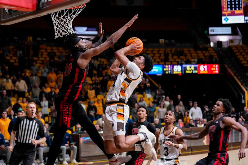 Feb 27, 2024; Laramie, Wyoming, USA; Wyoming Cowboys guard Kael Combs (11) shoots against UNLV Runnin' Rebels forward Keylan Boone (20) during the second half at Arena-Auditorium. Mandatory Credit: Troy Babbitt-USA TODAY Sports