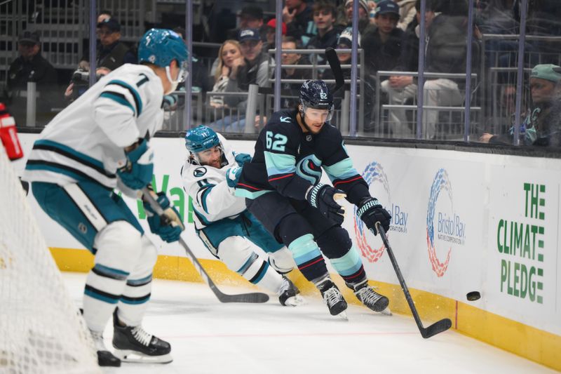 Nov 30, 2024; Seattle, Washington, USA; Seattle Kraken defenseman Brandon Montour (62) plays the puck off the boards while defended by San Jose Sharks center Luke Kunin (11) during the first period at Climate Pledge Arena. Mandatory Credit: Steven Bisig-Imagn Images