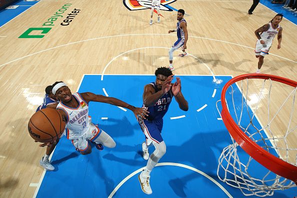 OKLAHOMA CITY, OK - NOVEMBER 25:  Shai Gilgeous-Alexander #2 of the Oklahoma City Thunder drives to the basket during the game as Joel Embiid #21 of the Philadelphia 76ers plays defense on November 25, 2023 at Paycom Arena in Oklahoma City, Oklahoma. NOTE TO USER: User expressly acknowledges and agrees that, by downloading and or using this photograph, User is consenting to the terms and conditions of the Getty Images License Agreement. Mandatory Copyright Notice: Copyright 2023 NBAE (Photo by Zach Beeker/NBAE via Getty Images)