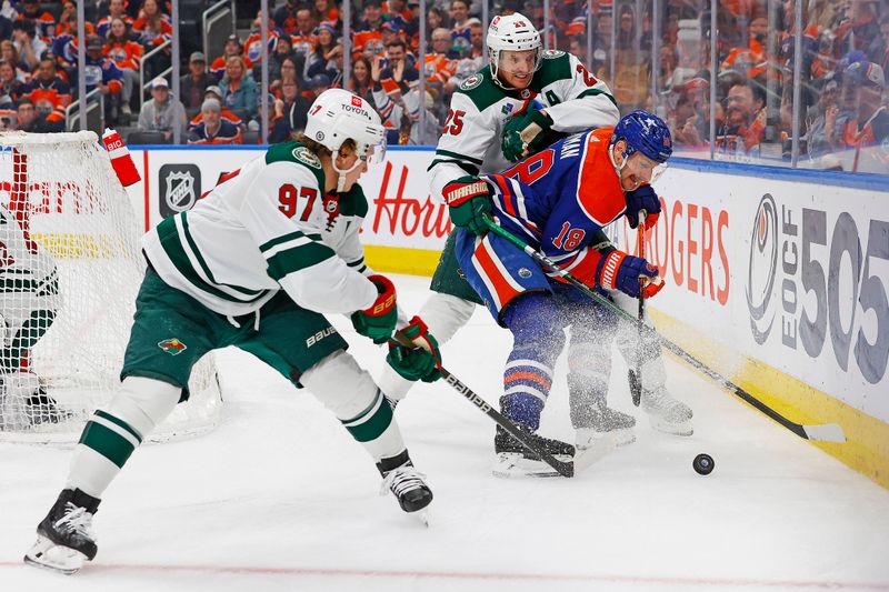 Feb 23, 2024; Edmonton, Alberta, CAN; Edmonton Oilers forward Zach Hyman (18) battles with Minnesota Wild forward Kirill Kaprizov (97) and  defensemen Jonas Brodin (25) Battle along the boards for a loose puck during the third period at Rogers Place. Mandatory Credit: Perry Nelson-USA TODAY Sports