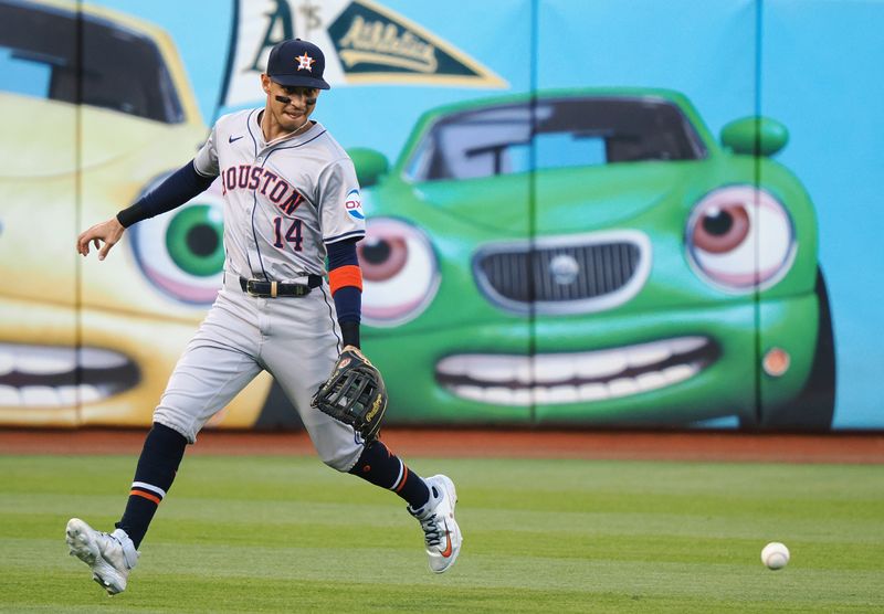 Jul 22, 2024; Oakland, California, USA; Houston Astros left fielder Mauricio Dubon (14) gathers the ball against the Oakland Athletics during the first inning at Oakland-Alameda County Coliseum. Mandatory Credit: Kelley L Cox-USA TODAY Sports