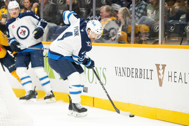 Nov 23, 2024; Nashville, Tennessee, USA;  Winnipeg Jets defenseman Neal Pionk (4) skates behind the net against the Nashville Predators during the first period at Bridgestone Arena. Mandatory Credit: Steve Roberts-Imagn Images