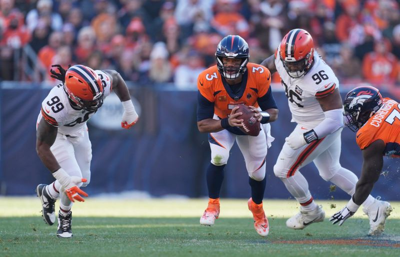 Denver Broncos quarterback Russell Wilson (3) escapes friom Cleveland Browns defensive end Za'Darius Smith (99) and Cleveland Browns defensive tackle Jordan Elliott (96) in the first half of an NFL football game Sunday, Nov. 26, 2023, in Denver. (AP Photo/David Zalubowski)