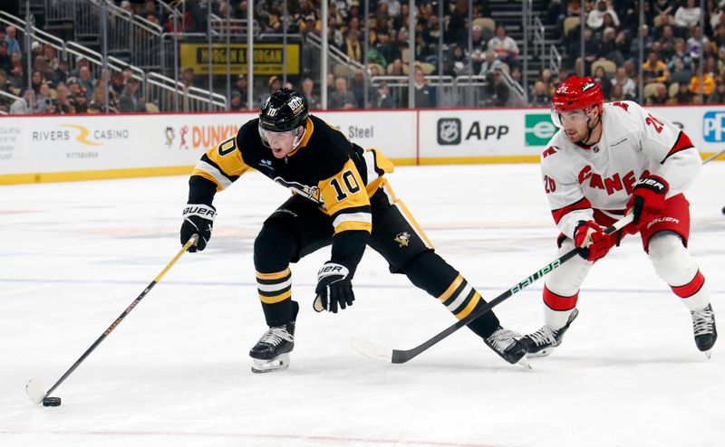 Oct 18, 2024; Pittsburgh, Pennsylvania, USA;  Pittsburgh Penguins left wing Drew O'Connor (10) skates up ice with the puck ahead of Carolina Hurricanes defenseman Sean Walker (26) during the first period at PPG Paints Arena. Mandatory Credit: Charles LeClaire-Imagn Images