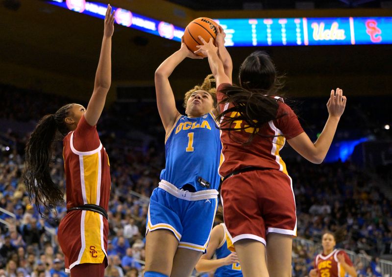 Dec 30, 2023; Los Angeles, California, USA; UCLA Bruins guard Kiki Rice (1) is defended by USC Trojans guard Taylor Bigby (1) and guard Kayla Padilla (45) as she goes for a basket in the first half at Pauley Pavilion presented by Wescom. Mandatory Credit: Jayne Kamin-Oncea-USA TODAY Sports