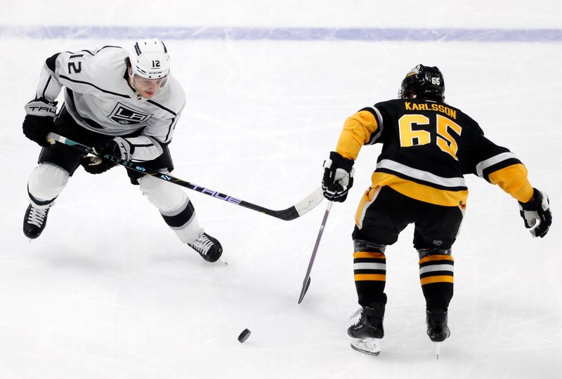 Feb 18, 2024; Pittsburgh, Pennsylvania, USA;  Los Angeles Kings left wing Trevor Moore (12) moves the puck around Pittsburgh Penguins defenseman Erik Karlsson (65) during the second period at PPG Paints Arena. Los Angeles won 2-1.Mandatory Credit: Charles LeClaire-USA TODAY Sports