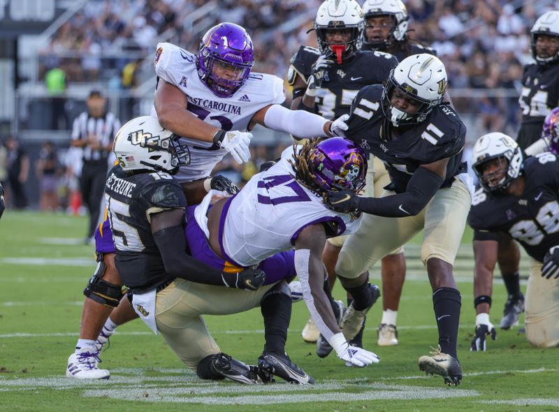 Oct 9, 2021; Orlando, Florida, USA; East Carolina Pirates running back Rahjai Harris (47) is tackled by UCF Knights linebacker Jeremiah Jean-Baptiste (11) and linebacker Tatum Bethune (15) during the first quarter at Bounce House. Mandatory Credit: Mike Watters-USA TODAY Sports