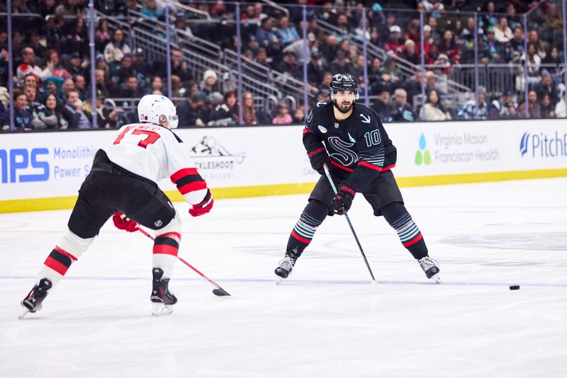 Jan 25, 2026; Seattle, Washington, USA; Seattle Kraken center Matty Beniers (10) looks to pass as New Jersey Devils defenseman Simon Nemec (17) defends during the third period at Climate Pledge Arena. Mandatory Credit: Blake Dahlin-Imagn Images