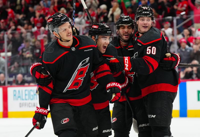 Nov 27, 2024; Raleigh, North Carolina, USA;  Carolina Hurricanes center Jesperi Kotkaniemi (82) is congratulated by defenseman Sean Walker (26) defenseman Shayne Gostisbehere (4) and left wing Eric Robinson (50) after his goal against the New York Rangers during the third period at Lenovo Center. Mandatory Credit: James Guillory-Imagn Images