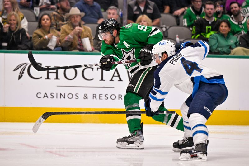 Oct 17, 2022; Dallas, Texas, USA; Dallas Stars center Tyler Seguin (91) shoots the puck as Winnipeg Jets defenseman Neal Pionk (4) defends during the second period at the American Airlines Center. Mandatory Credit: Jerome Miron-USA TODAY Sports