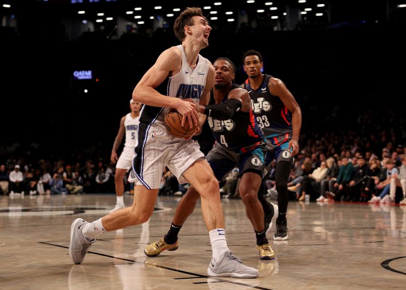 NEW YORK, NEW YORK - DECEMBER 02: Franz Wagner #22 of the Orlando Magic heads for the net as Dennis Smith Jr. #4 of the Brooklyn Nets defends during the second half at Barclays Center on December 02, 2023 in New York City. The Brooklyn Nets defeated the Orlando Magic 129-101. NOTE TO USER: User expressly acknowledges and agrees that, by downloading and or using this photograph, User is consenting to the terms and conditions of the Getty Images License Agreement. (Photo by Elsa/Getty Images)