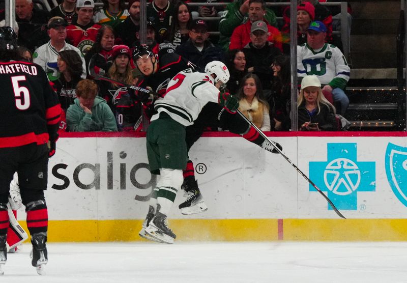 Jan 21, 2024; Raleigh, North Carolina, USA; Carolina Hurricanes right wing Jesper Fast (71) is checked by Minnesota Wild center Jacob Lucchini (27) during the first period at PNC Arena. Mandatory Credit: James Guillory-USA TODAY Sports