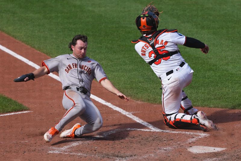 Sep 19, 2024; Baltimore, Maryland, USA; San Francisco Giants shortstop Brett Wisely (10) scores a run in the ninth inning ahead of a tag by Baltimore Orioles catcher Adley Rutschman (35) at Oriole Park at Camden Yards. Mandatory Credit: Mitch Stringer-Imagn Images