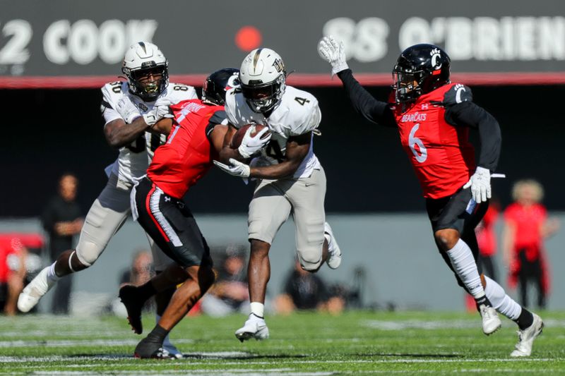 Oct 16, 2021; Cincinnati, Ohio, USA; UCF Knights wide receiver Ryan O'Keefe (4) runs with the ball against Cincinnati Bearcats cornerback Coby Bryant (7) and safety Bryan Cook (6) in the second half at Nippert Stadium. Mandatory Credit: Katie Stratman-USA TODAY Sports