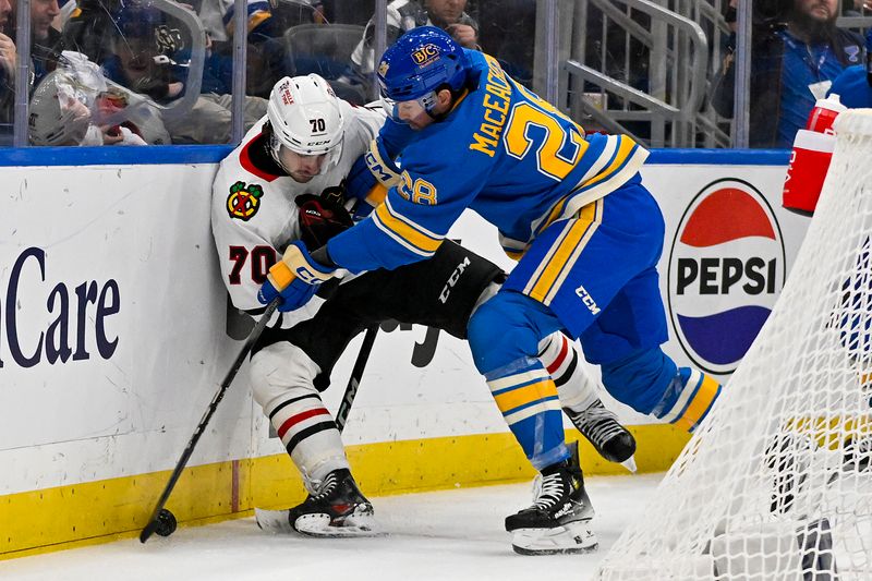 Dec 23, 2023; St. Louis, Missouri, USA;  St. Louis Blues left wing Mackenzie MacEachern (28) checks Chicago Blackhawks center Cole Guttman (70) during the second period at Enterprise Center. Mandatory Credit: Jeff Curry-USA TODAY Sports