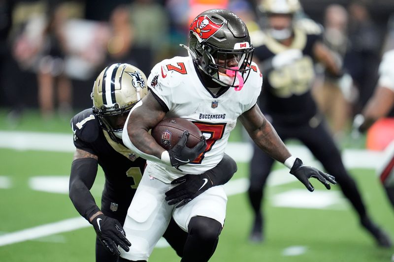 Tampa Bay Buccaneers running back Bucky Irving (7) runs against New Orleans Saints cornerback Alontae Taylor (1) during the second half of an NFL football game in New Orleans, Sunday, Oct. 13, 2024. (AP Photo/Michael Conroy)