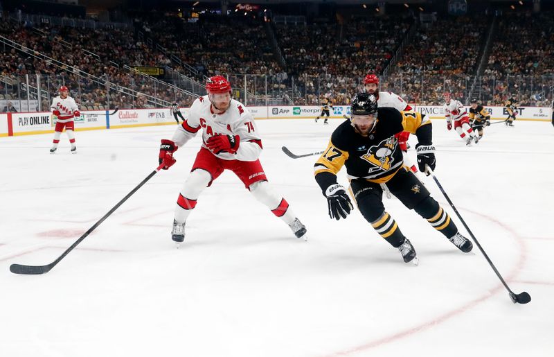 Oct 18, 2024; Pittsburgh, Pennsylvania, USA;  Pittsburgh Penguins right wing Bryan Rust (17) moves the puck ahead of Carolina Hurricanes defenseman Jaccob Slavin (74) during the first period at PPG Paints Arena. Mandatory Credit: Charles LeClaire-Imagn Images