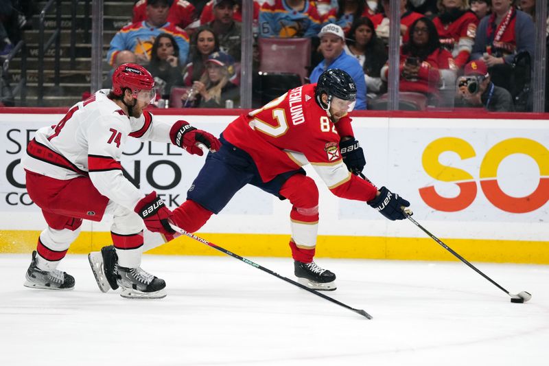 Nov 10, 2023; Sunrise, Florida, USA; Florida Panthers center Kevin Stenlund (82) controls the puck away from Carolina Hurricanes defenseman Jaccob Slavin (74) during the second period at Amerant Bank Arena. Mandatory Credit: Jasen Vinlove-USA TODAY Sports