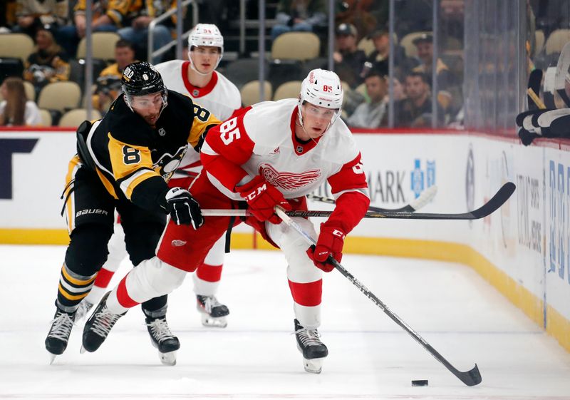 Oct 1, 2024; Pittsburgh, Pennsylvania, USA;  Detroit Red Wings left wing Elmer Soderblom (85) moves the puck up ice ahed of Pittsburgh Penguins left wing Michael Bunting (8) during the second period at PPG Paints Arena. Detroit won 2-1. Mandatory Credit: Charles LeClaire-Imagn Images