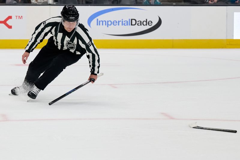Oct 1, 2025; San Jose, California, USA; Linesperson Kiel Murchison (79) picks up two pieces of a broken stick during the second period of a preseason game between the San Jose Sharks and the Anaheim Ducks at SAP Center at San Jose. Mandatory Credit: Robert Edwards-Imagn Images