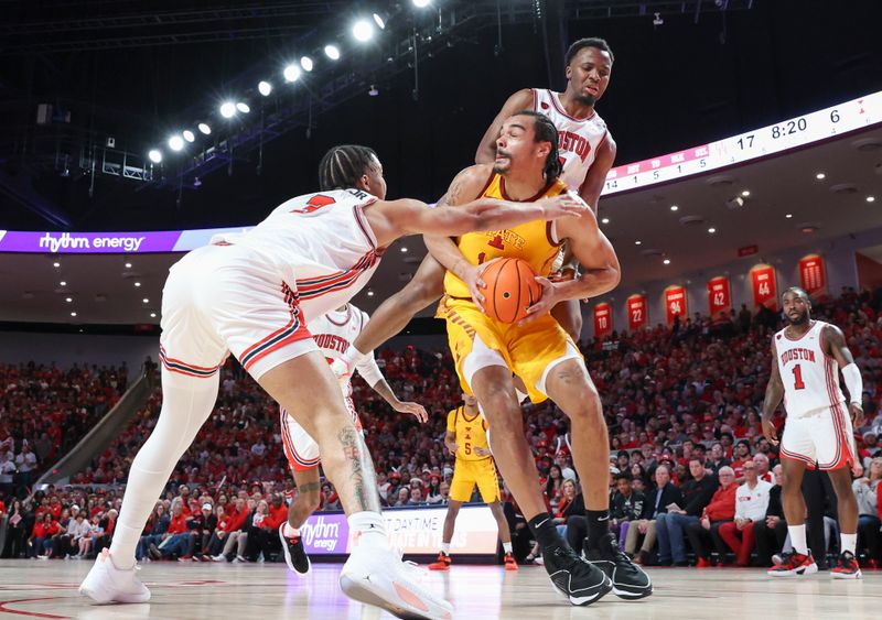 Feb 19, 2024; Houston, Texas, USA; Iowa State Cyclones forward Robert Jones (12) attempts to control the ball as Houston Cougars guard Ramon Walker Jr. (3) and guard L.J. Cryer (4) defend during the first half at Fertitta Center. Mandatory Credit: Troy Taormina-USA TODAY Sports