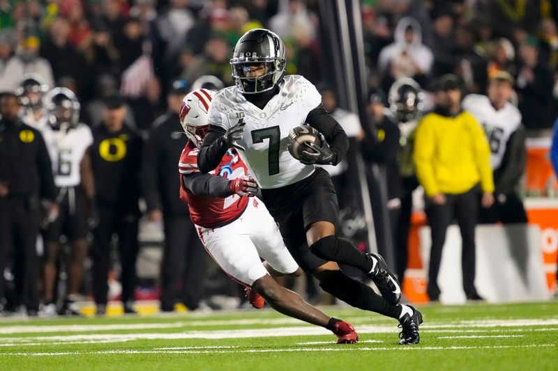 Nov 16, 2024; Madison, Wisconsin, USA;  Oregon Ducks wide receiver Evan Stewart (7) rushes with the football in front of Wisconsin Badgers cornerback Ricardo Hallman (2) after catching a pass during the fourth quarter at Camp Randall Stadium. Mandatory Credit: Jeff Hanisch-Imagn Images