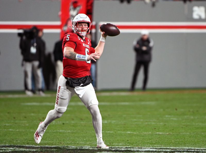 Nov 25, 2023; Raleigh, North Carolina, USA; North Carolina State Wolfpack quarterback Brennan Armstrong (5) throws a pass against the North Carolina Tar Heels during the first half at Carter-Finley Stadium. Mandatory Credit: Rob Kinnan-USA TODAY Sports