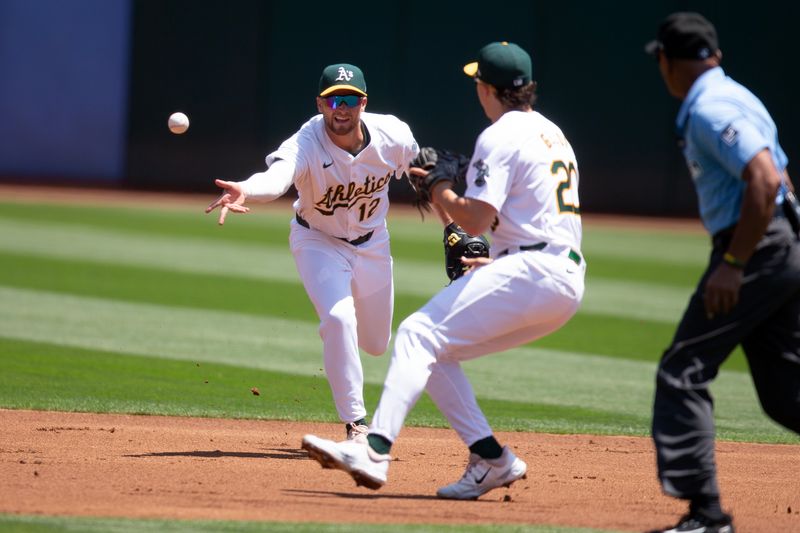 Jul 24, 2024; Oakland, California, USA; Oakland Athletics shortstop Max Schuemann (12) flips the ball to second baseman Zack Gelof (20) to retire Houston Astros third baseman Alex Bregman (not pictured) at second base during the first inning at Oakland-Alameda County Coliseum. Mandatory Credit: D. Ross Cameron-USA TODAY Sports