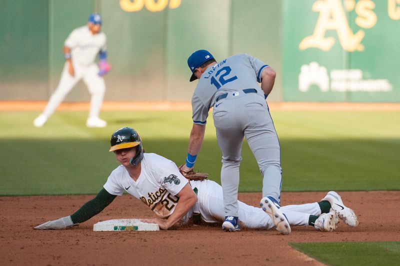 Jun 18, 2024; Oakland, California, USA; Kansas City Royals second base Nick Loftin (12) attempts to tag out Oakland Athletics second base Zack Gelof (20) at second base during the third inning at Oakland-Alameda County Coliseum. Mandatory Credit: Ed Szczepanski-USA TODAY Sports