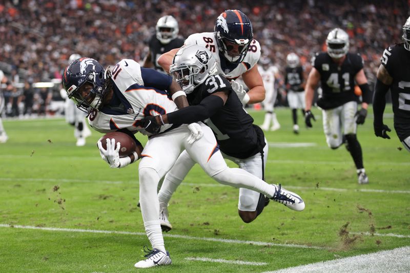 Denver Broncos wide receiver Jerry Jeudy, right, pushes his way through the tackle attempt of Las Vegas Raiders cornerback Brandon Facyson (31) before scoring a touchdown during the first half of an NFL football game, Sunday, Jan. 7, 2024 in Las Vegas. (AP Photo/Ellen Schmidt)