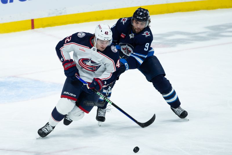 Jan 9, 2024; Winnipeg, Manitoba, CAN; Columbus Blue Jackets forward Alexandre Texier (42) skates with the puck as Winnipeg Jets forward Alex Iafallo (9) defends during the third period at Canada Life Centre. Mandatory Credit: Terrence Lee-USA TODAY Sports