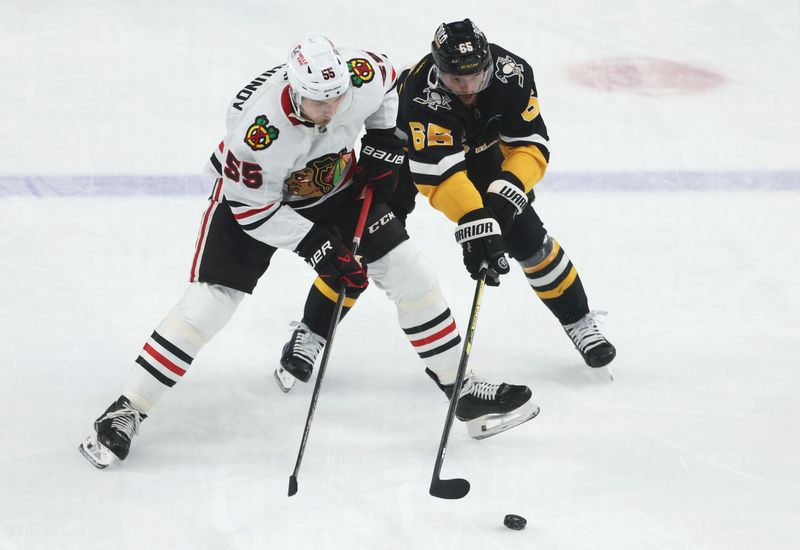 Apr 8, 2025; Pittsburgh, Pennsylvania, USA;  Chicago Blackhawks defenseman Artyom Levshunov (55) and Pittsburgh Penguins defenseman Erik Karlsson (65) chase the puck during the second period at PPG Paints Arena. Mandatory Credit: Charles LeClaire-Imagn Images