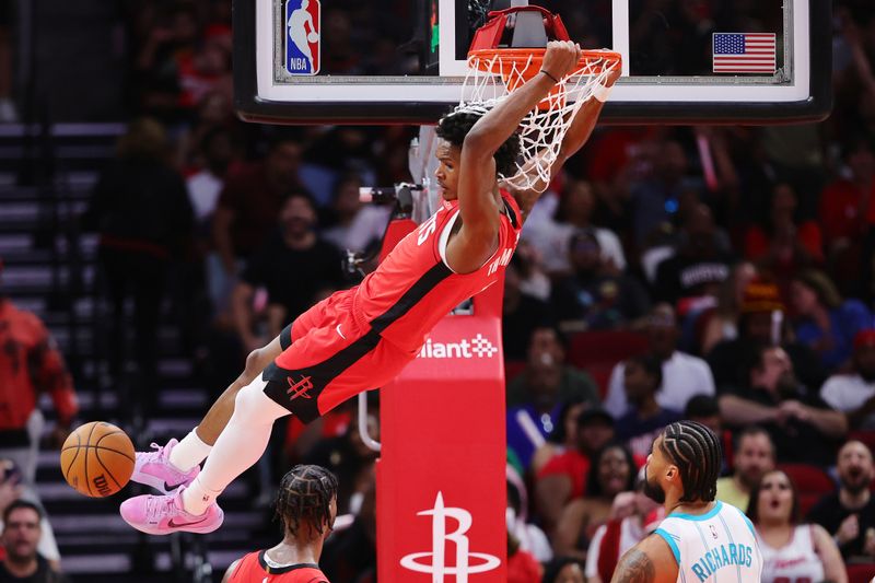 HOUSTON, TEXAS - OCTOBER 23: Amen Thompson #1 of the Houston Rockets hangs from the basket after slam dunking the ball in the first half against the Charlotte Hornets at Toyota Center on October 23, 2024 in Houston, Texas.  NOTE TO USER: User expressly acknowledges and agrees that, by downloading and or using this photograph, User is consenting to the terms and conditions of the Getty Images License Agreement. (Photo by Alex Slitz/Getty Images)