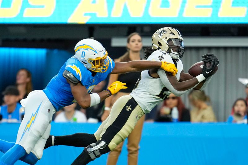 New Orleans Saints running back Kendre Miller (25) pulls in a pass reception near the end zone as Los Angeles Chargers linebacker Daiyan Henley (0) covers in the first half of an NFL football game in Inglewood, Calif., Sunday, Aug. 20, 2023. (AP Photo/Marcio Jose Sanchez)